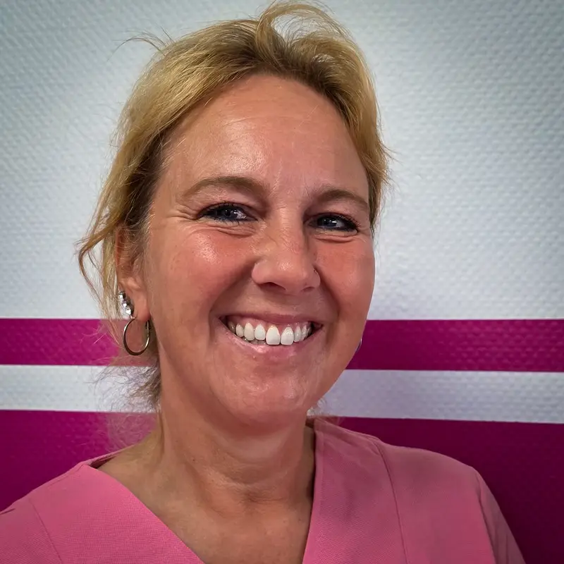 Neutrale Frau mit blondem Haar, rosa Oberteil, Creolen vor Pinkwand